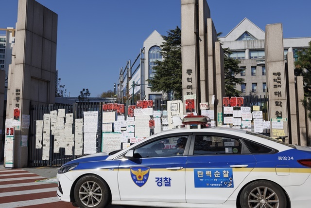 【동덕여대 정문】 24일 오후 남녀공학 전환 반대 유인물이 가득한 서울 성북구 동덕여대 정문 앞에 경찰 순찰차가 대기하고 있다. 동덕여대가 남녀공학 전환 논의를 중단하기로 하며 학생들의 점거 농성은 일단락됐지만, 이번 사태를 둘러싼 논란은 끊이지 않고 있다. 이른바 '래커칠'로 상징되는 학교 측의 시위 피해에 대해 누가 책임을 지느냐 하는 문제는 여전히 양측 갈등의 불씨가 될 가능성이 높은 상태다. 2024.12.5. / 연합뉴스