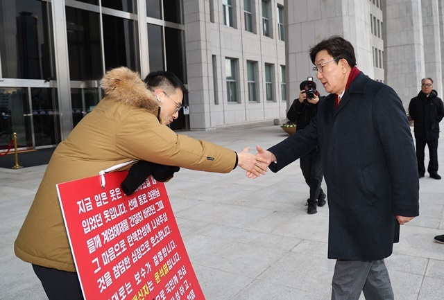 국민의힘 권성동 신임 원내대표가 13일 오전 국회 본청 앞에서 탄핵 찬성을 호소하는 김상욱 의원과 악수하고 있다. 2024.12.13. / 연합뉴스