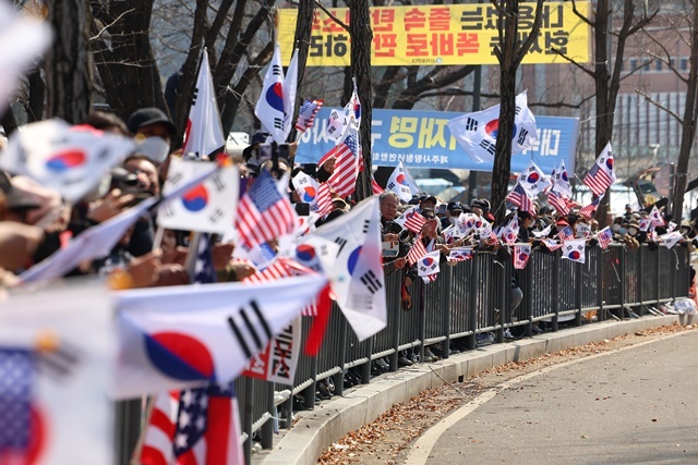 법원의 윤석열 대통령 구속 취소 결정을 두고 검찰의 입장 발표가 늦어지고 있는 가운데 8일 경기도 의왕시 서울구치소 앞에서 윤 대통령 지지자들이 석방을 기대하며 태극기와 성조기를 흔들고 있다. 2025.3.8. / 연합뉴스