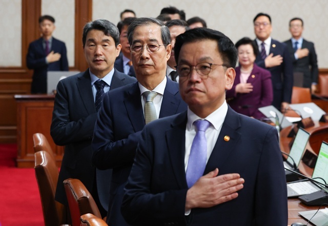 한덕수 대통령 권한대행 국무총리가 1일 정부서울청사에서 열린 국무회의에서 국기에 경례를 하고 있다. 오른쪽부터 최상목 부총리 겸 기획재정부 장관, 한 권한대행, 이주호 부총리 겸 교육부 장관. 2025.5.2. / 연합뉴스