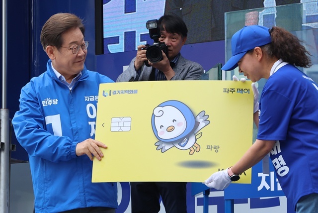 더불어민주당 이재명 대선 후보가 20일 경기 파주시 금릉역 중앙광장에서 열린 유세에서 지역화폐 모형을 전달받고 있다. / 연합뉴스