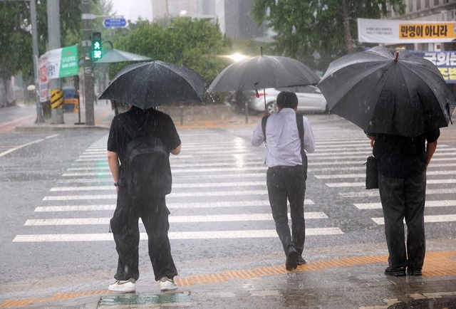 서울 서남권에 호우주의보가 발효된 8일 서울 영등포구 여의도 국회 인근에서 시민들이 우산을 쓰고 있다. / 연합뉴스