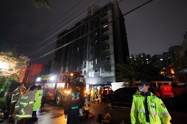 18일 소방대원이 전날 주차장에 불이 난 경기도 광명시 소하동 한 아파트에서 인명 수색하는 가운데 경찰이 현장을 통제하고 있다. / 연합뉴스