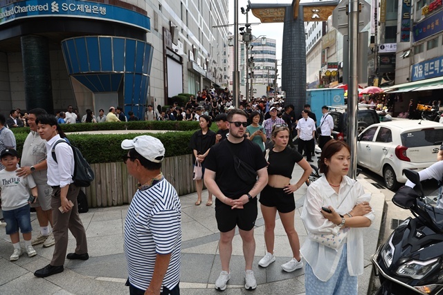 지난 5일 서울 중구 명동 신세계백화점 본점에 폭발물을 설치했다는 협박 글이 인터넷 커뮤니티에 올라와 경찰이 수색에 나선 가운데 사람들이 건물 밖으로 대피해 있다. / 연합뉴스